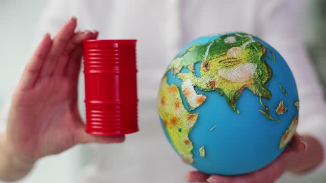 Oil barrel with petroleum products and globe in hands