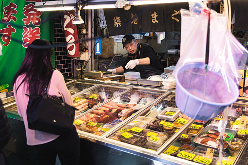 Tokyo, Japan - April 12, 2023: fish shop on Tsukiji Fish Market with unidentified people. It is a major tourist attraction. Before 2018, it was the largest wholesale fish market in the world