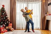 A festive senior couple is dancing and having fun at home on christmas and new year.