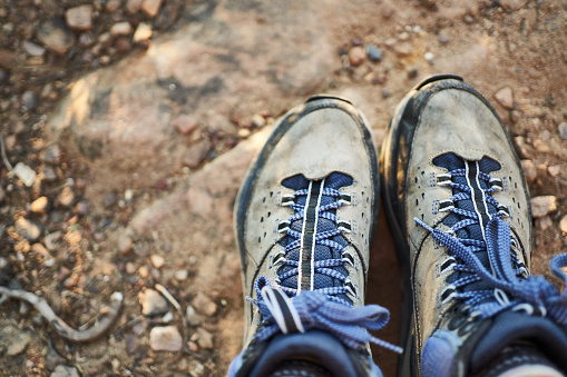 Close-up image of a pair of hiking boots on a rocky mountain trail