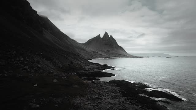 Aerial vesturhorn mountain, black sand beach stokksnes, flying over volcanic dark moody rocks, moody scenery, Iceland