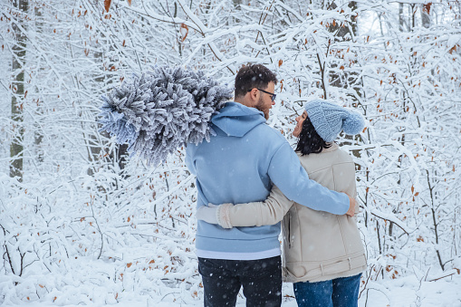 man and woman looking at each other hugging in winter forest