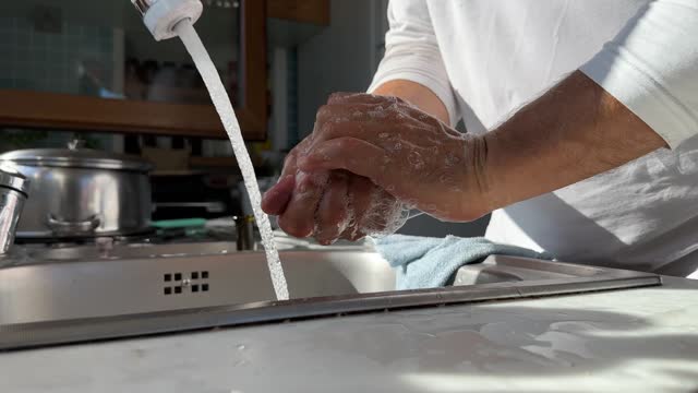 Young man washing male hands with soap under water, close up. 4k video.