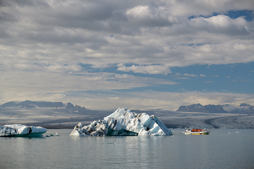 Hofn, Iceland - September 9, 2022: Tourists riding in small boat close to icebergs floating in Jokusarlon lake near Hofn in Iceland during september 2022