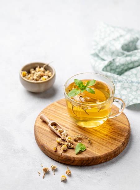istock Chamomile herbal tea in a glass cup with mint on a light background with dry flowers. The concept of a healthy detox drink for health and sleep. 1798971809