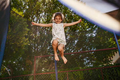 Siblings having fun as they jump on trampoline