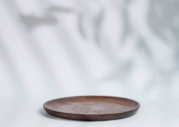 istock Abstract empty wooden plate with shadows leaves on a gray background. Layout concept for promotional product presentation, sale or cosmetics display. 1798985300