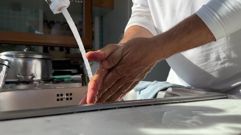 Young man washing male hands with soap under water, close up. 4k video.