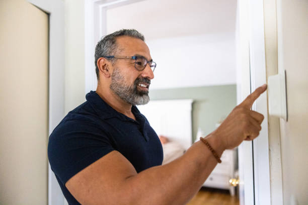 istock Mature man using smart thermostat at home 1798992467