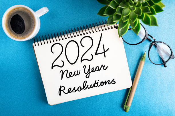 istock New year resolutions 2024 on desk. 2024 goals list with notebook, coffee cup, plant on blue table. Resolutions, plan, goals, action, checklist, idea concept. New Year 2024 resolutions. Copy space 1799021483