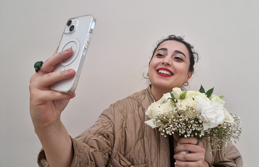 Happy Young woman holding flowers and taking selfie
