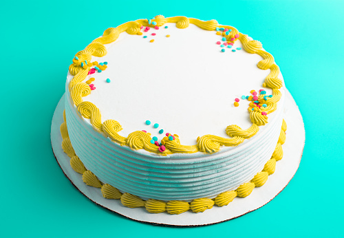 A Circular White Ice Cream Cake with Colorful Border and Sprinkles