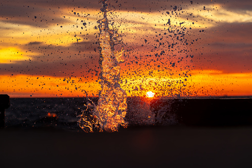 Sea waves splash with sunset background.