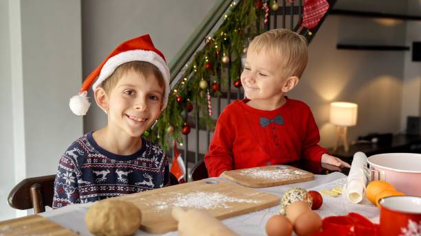 istock Two smiling boys in Santa's hat having fun while sitting on kitchen on a Christmas. Winter holidays, celebrations and party. 1799059251