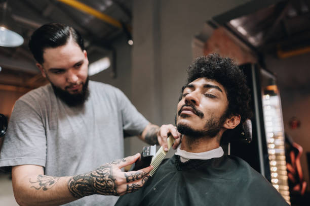 Barber shaving customer's beard in a barber shop