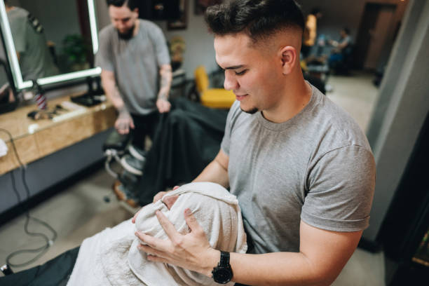 Barber wrapping customer's head with towel in a barber shop