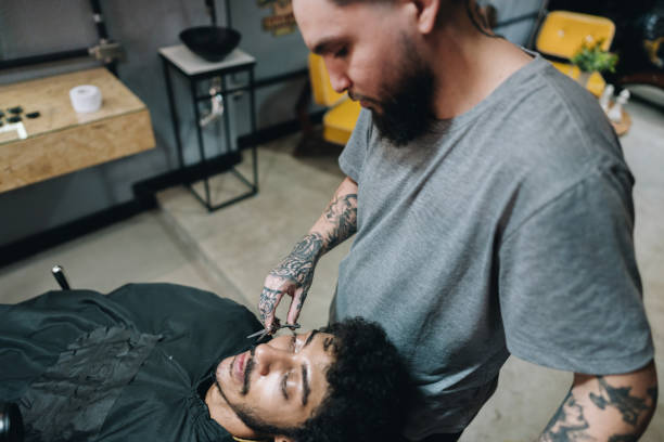 Barber shaving costumer's beard in a barber shop