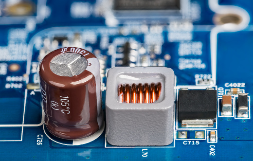 Blue power supply printed circuit board with surface mounted electronic components and brown condenser or gray coil