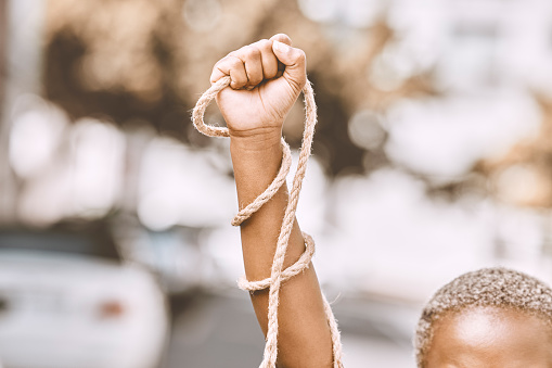 Hand, rope and fist protest slavery for freedom and human rights against an urban background. Activist, activism and rebellion against racism and change for civil, law and government rights