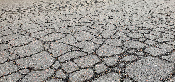 The sidewalk and roadway part for transport needs repair. Old road with cracked, damaged, destroyed, worn, broken, broken, dirty asphalt. Cracks in the asphalt on the highway. Cracked bitumen