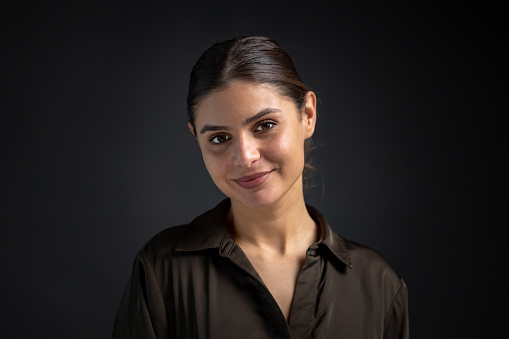 portrait of a young smiling woman in a green shirt on dark background