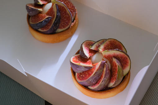 Healthy fruit pastry dessert. Fig and cheese tartlets or cake with ripe figs top view in eco take away packing. bakery small business concept