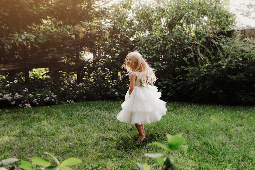 A beautiful little girl, four years old, dancing in a garden.