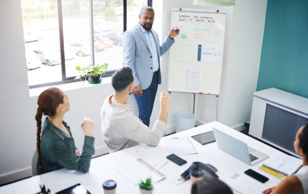 istock Coach, training and black man with presentation in meeting for strategy and progress in startup. Teaching, business growth and boss planning with staff for profit in economy with analysis or numbers 1799304355