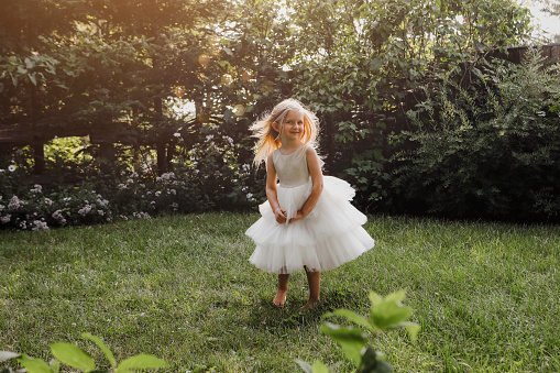 A beautiful little girl, four years old, dancing in a garden.