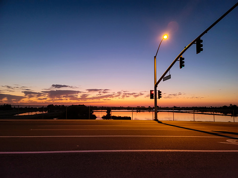 A street light next to a body of water reflecting a beautiful sunset in Bakersfield, California.