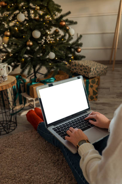 istock Young woman work on laptop computer with blank display screen with mockup copy space. Modern home living room interior design. Christmas, New Year decorated workspace 1799363388