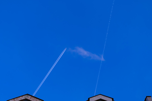 airplane contrails in the clear blue sky over the roofs