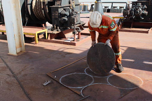 at sea, on board ship - november 15, 2023 : crew member of ship fabricating steel plates in round shape on deck