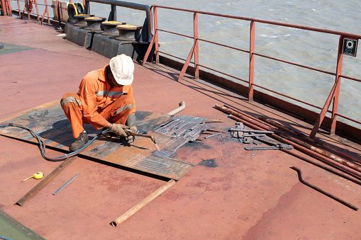 at sea, onboard ship - november 15, 2023 : fitter on board ship fabricating steel plate using gas cutter on deck
