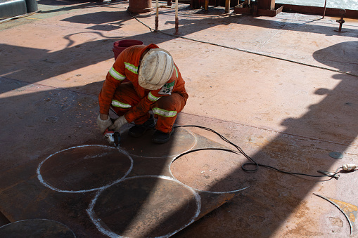 at sea on board ship - november 15, 2023 : deck fitter fabricating steel plates in round shape on deck