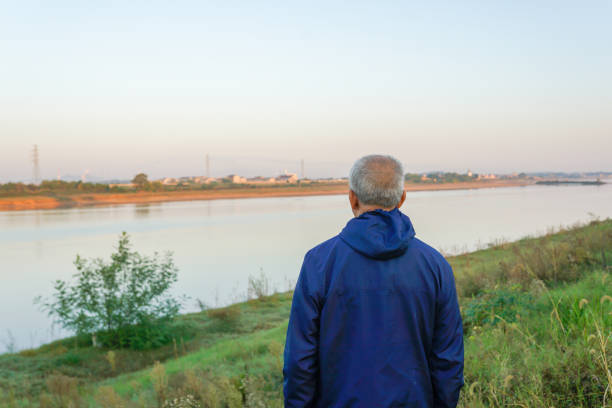 old man standing in front of the river