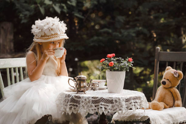niña que tiene una fiesta de té en un jardín - tea party dressing up little girls hat fotografías e imágenes de stock