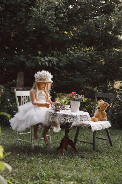 niña que tiene una fiesta de té en un jardín - tea party dressing up little girls hat fotografías e imágenes de stock