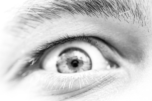 Black and white closeup eye of young man, front view, full frame horizontal composition