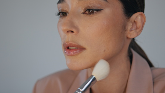 Makeup blogger applying face powder filming tutorial closeup. Woman powdering