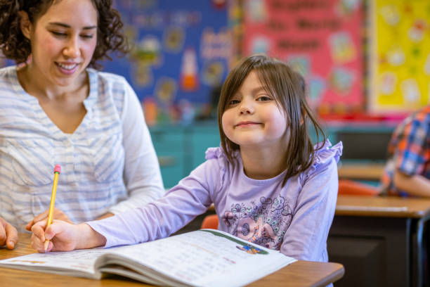 istock Young girl smiles, working on schoolwork with teacher 1799467333