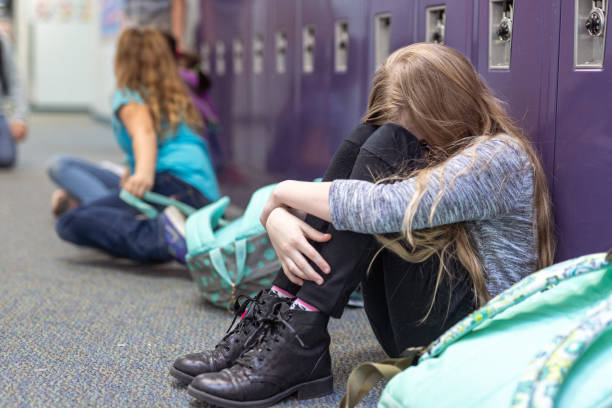 istock Upset student sits on floor in front of lockers 1799467875