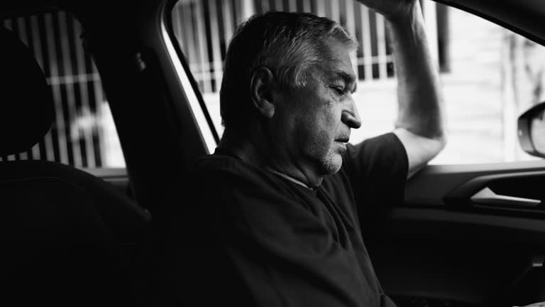 Lonely Older Person in Desperate Dire Circumstances, Struggling in Quiet Despair Inside Parked Car, dramatic monochromatic, black and white