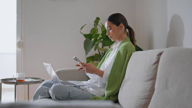 istock Relaxed girl checking cellphone working home sofa alone. Woman learning online 1799493520