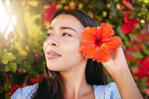 Woman, flower and garden on vacation in Hawaii, having fun  in summer and nature. Mexican female in a zen park, relax and content while picking pretty flowers and enjoying freedom, fresh air and sun