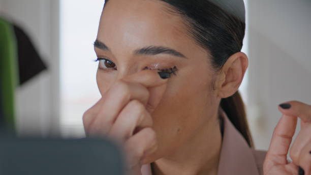 istock Focused woman applying eyelashes makeup at studio closeup. Lady decorating eyes 1799500045