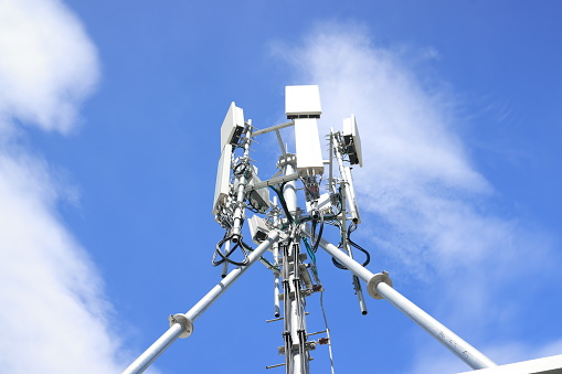 Cell phone or broadcast transmitter antenna tower with clouds background
