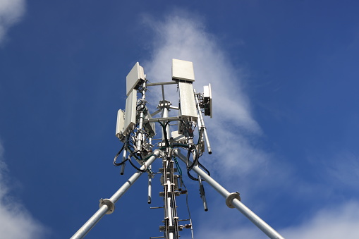 Cell phone or broadcast transmitter antenna tower with clouds background
