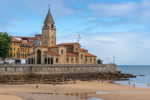 View of the church of San Pedro with the beach of San Lorenzo with low tide. Gijon Spain. August 1, 2023.