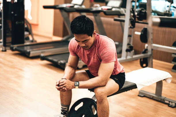 молодые азиатские спортсмены проверяют спортивные часы после тренировки. - body care asian ethnicity body building toughness стоковые фото и изображения
